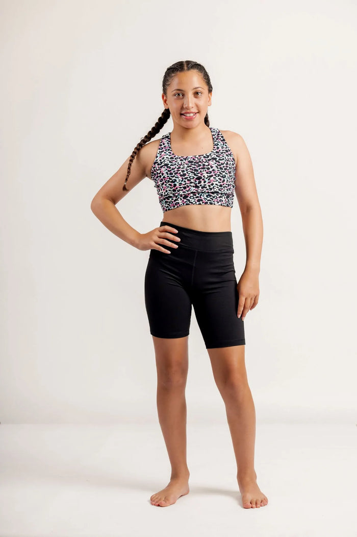 Girl wearing a Multi coloured leopard print crop top and black Get Moving Bike Shorts on a white background
