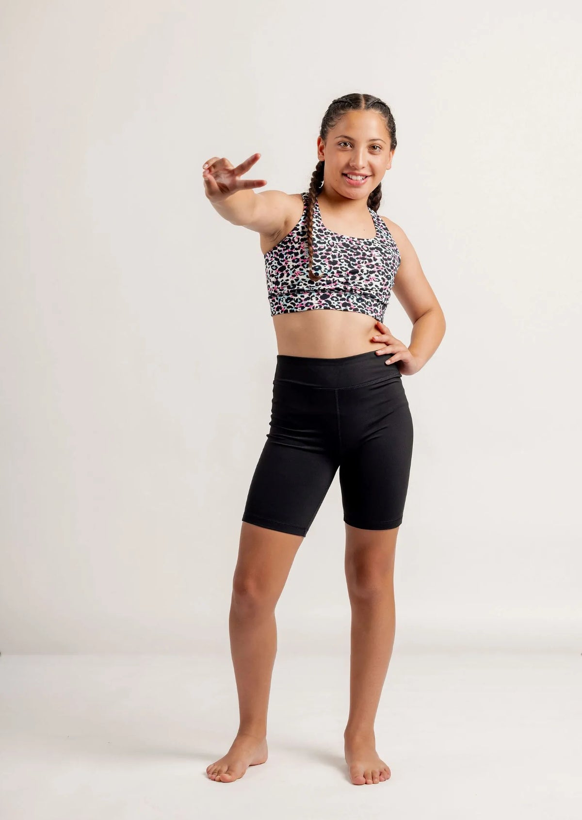 Girl wearing a Multi coloured leopard print crop top and black Get Moving Bike Shorts on a white background