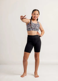 Girl wearing a Multi coloured leopard print crop top and black Get Moving Bike Shorts on a white background