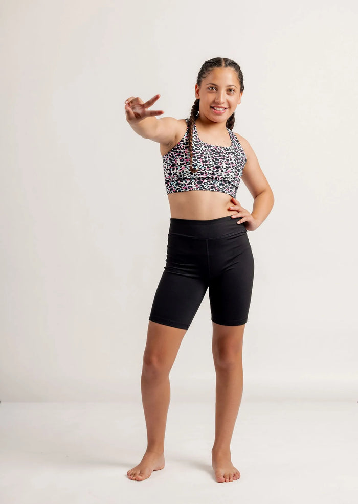 Girl wearing a Multi coloured leopard print crop top and black Get Moving Bike Shorts on a white background