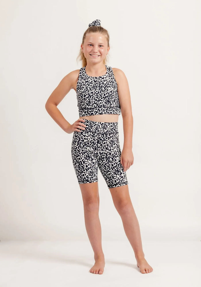 Young girl wearing Snow Leopard print sports outfit on a white background