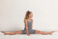 Girl in a Snow Leopard print sports outfit performing a split on a white background