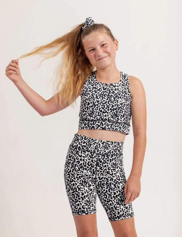 Young girl wearing an Ignite snow leopard print crop top and shorts on a white background