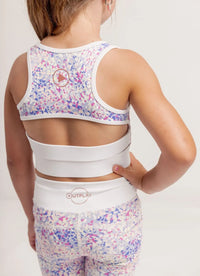 Girl wearing a Confetti coloured sports bra and Get Moving Bike shorts with 'Outplay' branding on a light background