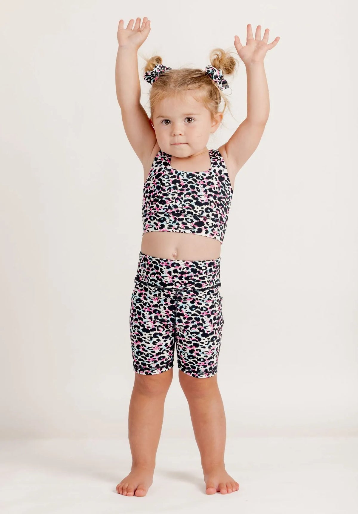 Girl wearing an Envy Me Multi coloured leopard print crop and Get Moving bike shorts set on a white background