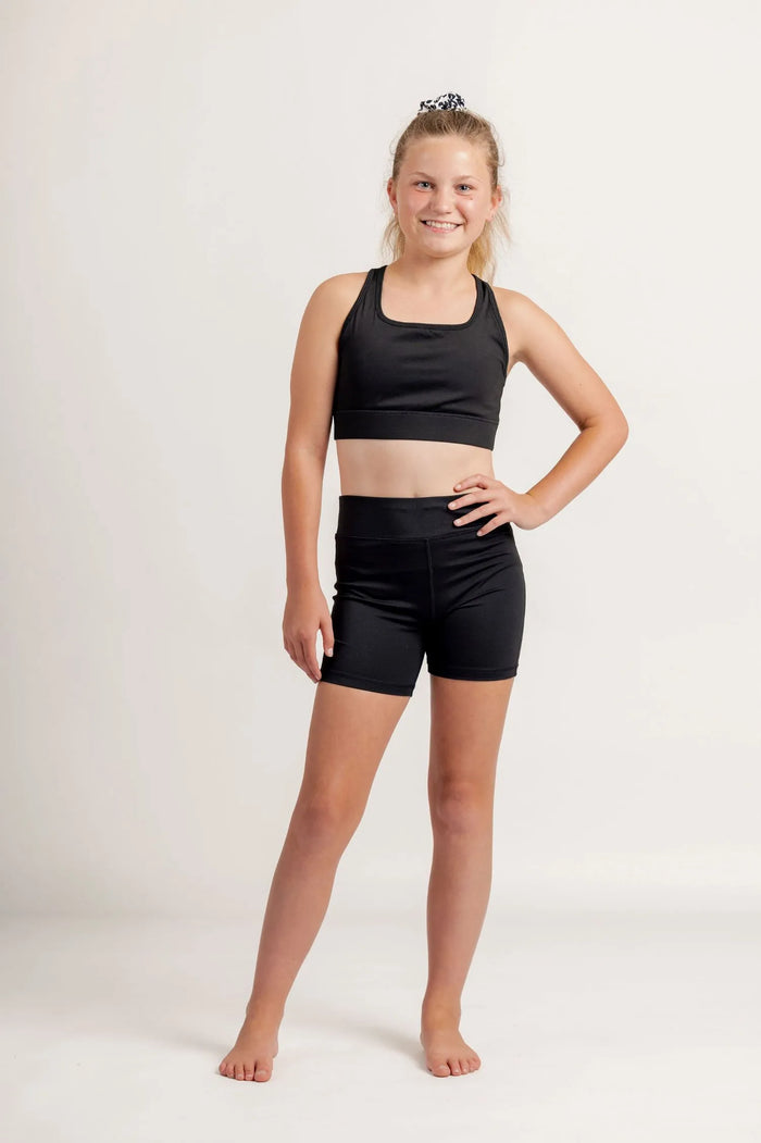 Girl wearing a Race ready black crop and black shorts on a light background