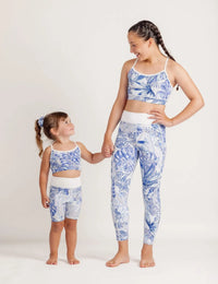 Two children wearing matching blue Monstera outfits on a plain background