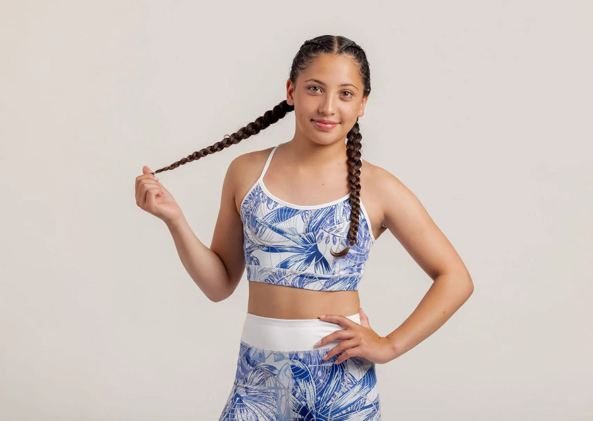Girl in a Fearless Blue Monstera crop and shorts posing with braided hair against a plain background