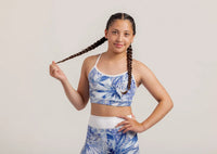 Girl in a Fearless Blue Monstera crop and shorts posing with braided hair against a plain background