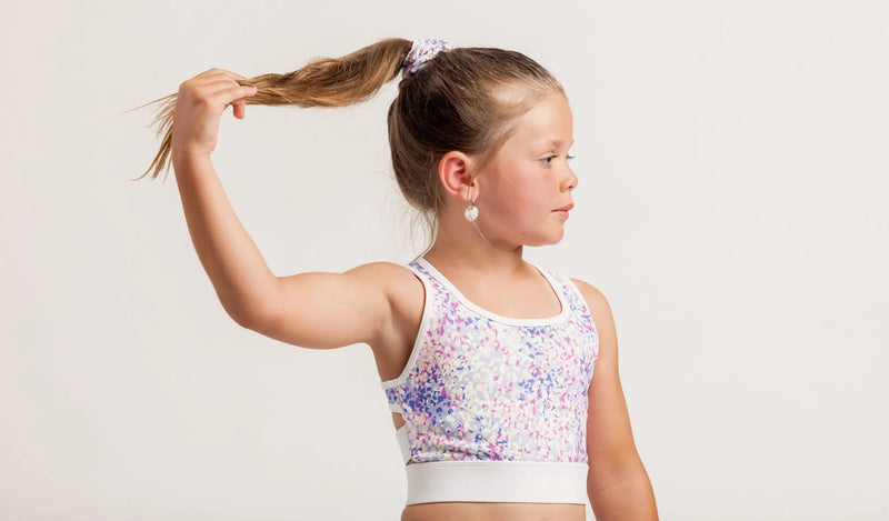 Young girl in a colorful sports crop against a plain background