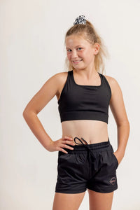 Girl wearing a Race ready black crop and black shorts on a light background