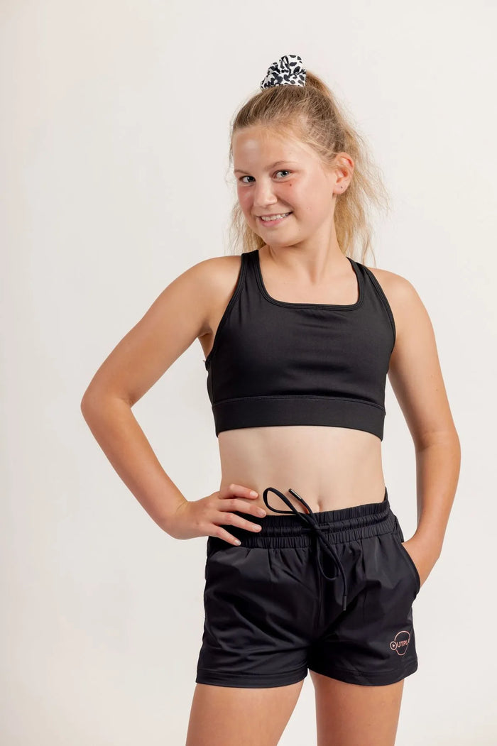 Girl wearing a Race ready black crop and black shorts on a light background