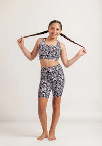 Girl wearing an Envy Me Multi coloured leopard print crop and bike shorts set on a white background
