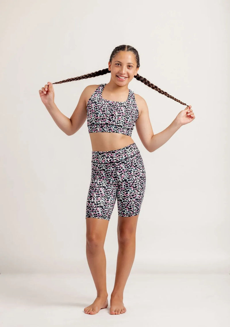 Girl wearing an Envy Me Multi coloured leopard print crop and bike shorts set on a white background