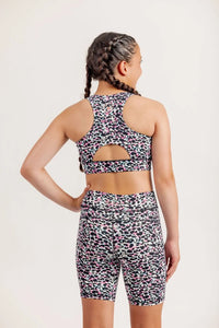 Girl wearing an Envy Me Multi coloured leopard print crop and bike shorts set on a white background