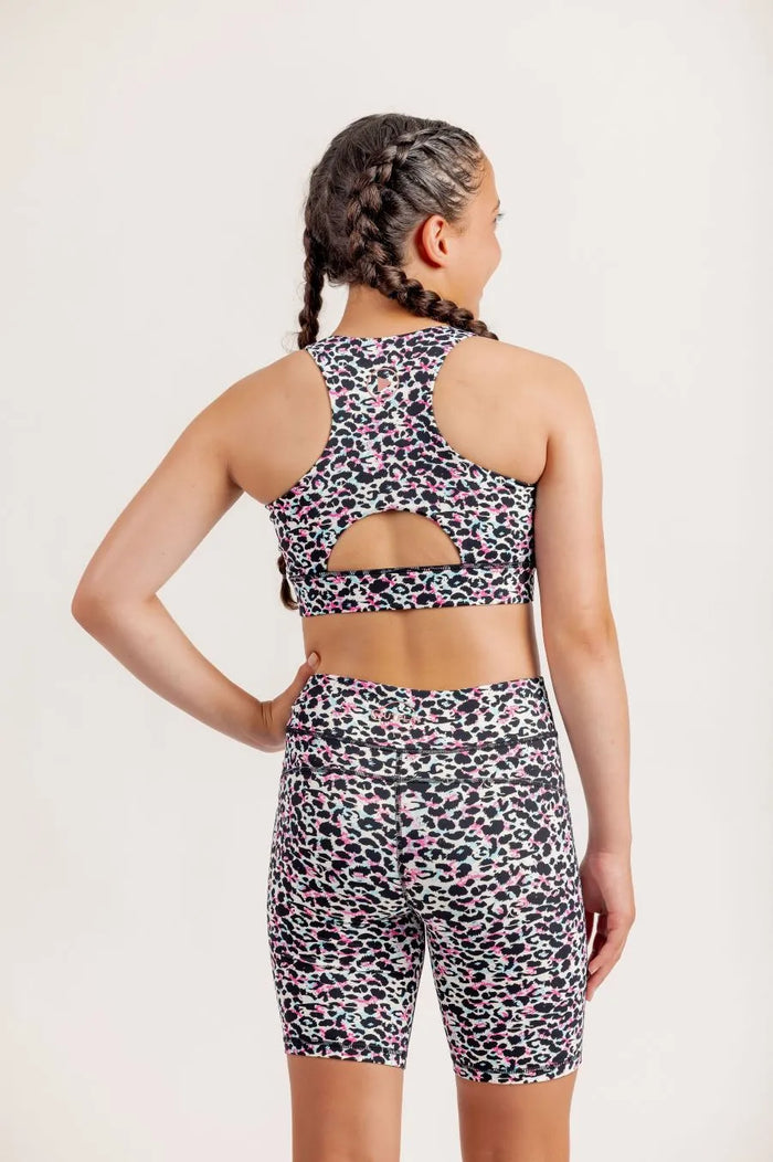 Girl wearing an Envy Me Multi coloured leopard print crop and bike shorts set on a white background