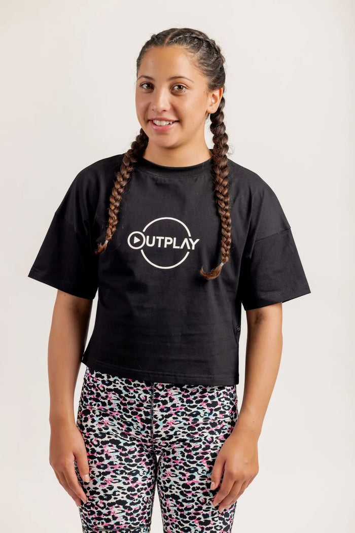 Girl wearing Black crop Tshirt and multicoloured bike shorts on a light background