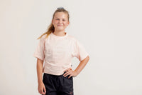 Girl wearing a light pink crop Tshirt and black shorts on a light background