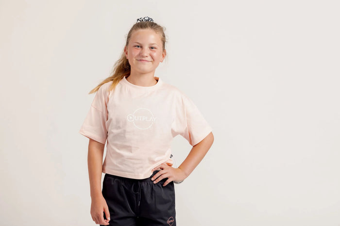 Girl wearing a light pink crop Tshirt and black shorts on a light background