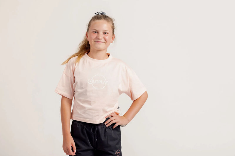 Girl wearing a light pink crop Tshirt and black shorts on a light background