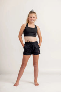 Girl in a black crop and black jogger shorts on a light background