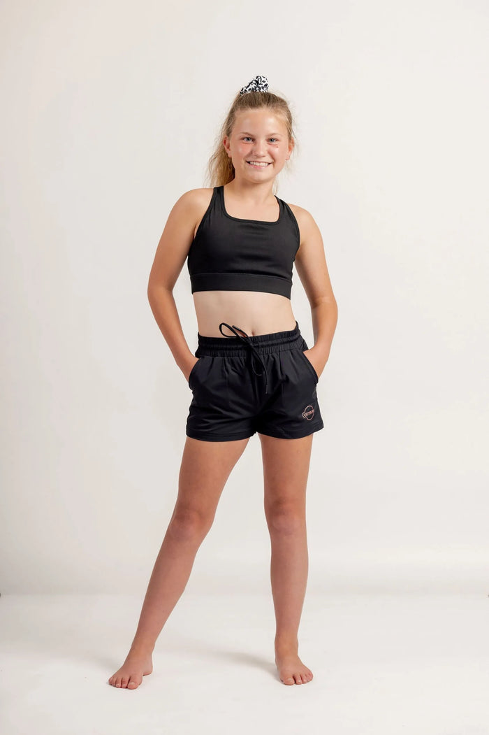 Girl in a black crop and black jogger shorts on a light background