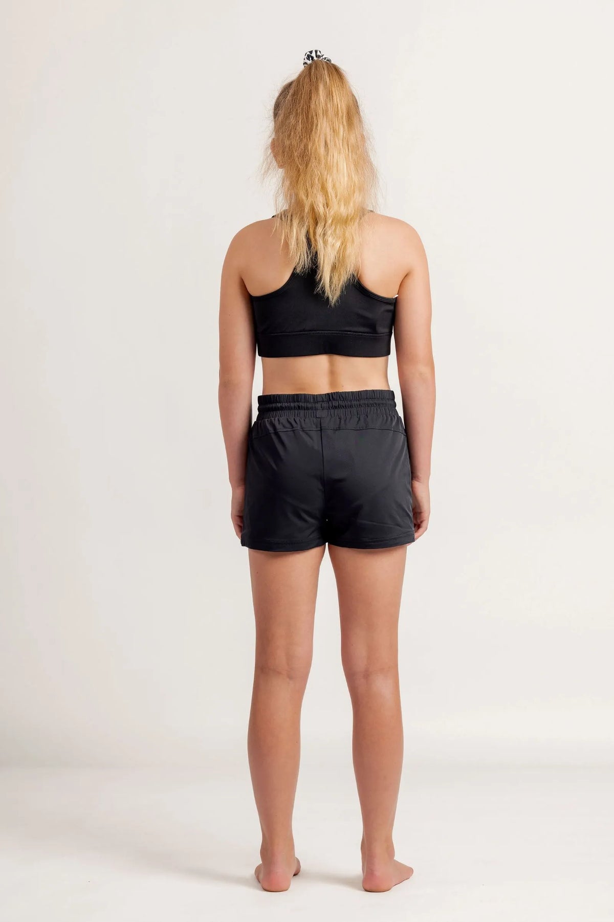 Girl in a black crop and black jogger shorts on a light background