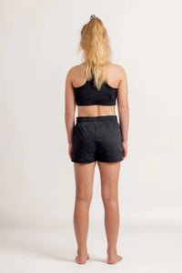 Girl in a black crop and black jogger shorts on a light background