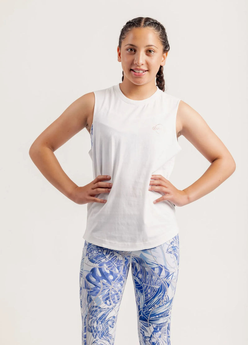 Girl wearing a Shine Bright white sleeveless top and Limitless Blue Monstera patterned leggings on a white background