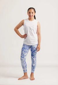 Girl wearing a Shine Bright white sleeveless top and Limitless Blue Monstera patterned leggings on a white background