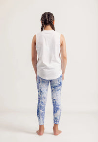 Girl wearing a Shine Bright white sleeveless top and Limitless Blue Monstera patterned leggings on a white background