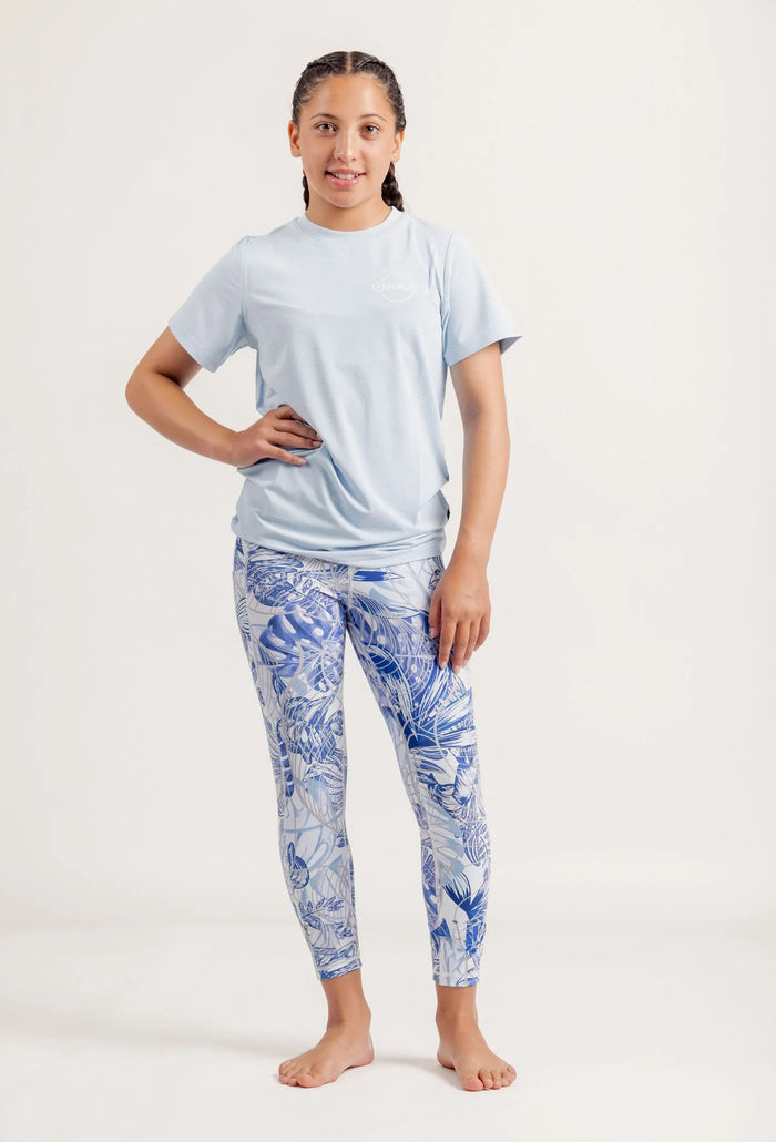 Girl wearing a light blue t-shirt and Blue Monstera Limitless leggings on a white background