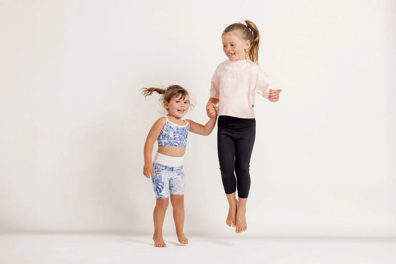 Two young girls in athletic wear standing on a white background