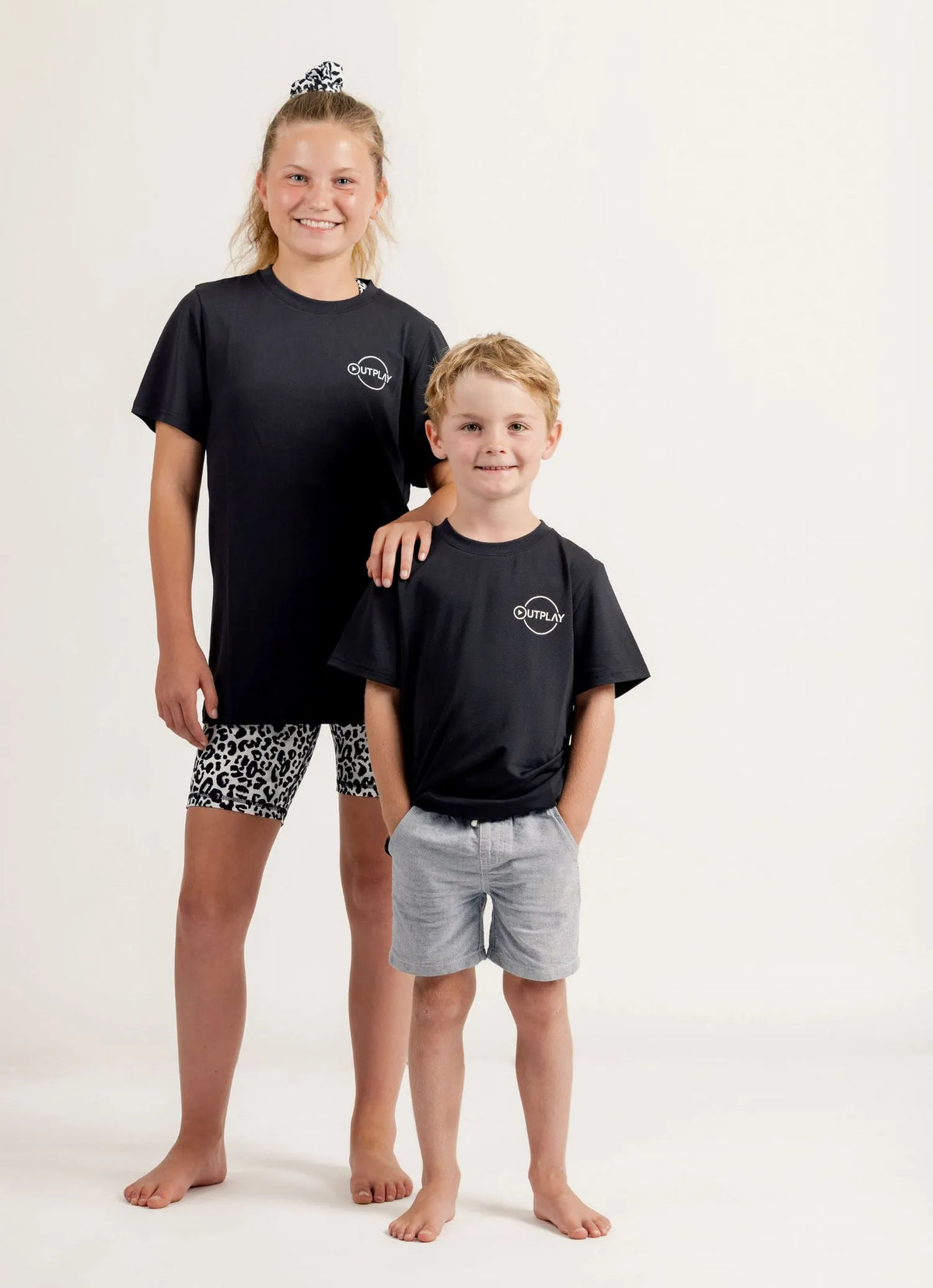 Two children wearing Gametime black t-shirts with a logo on a white background