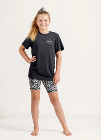 Young girl wearing a Gametime black t-shirt and Ignite Snow Leopard patterned bike shorts on a white background
