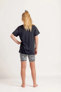 Girl wearing a Gametime black t-shirt and Ignite Snow Leopard patterned bike shorts on a white background