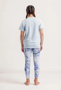 Girl wearing a Gametime light blue t-shirt and Limitless Blue Monstera patterned leggings on a white background